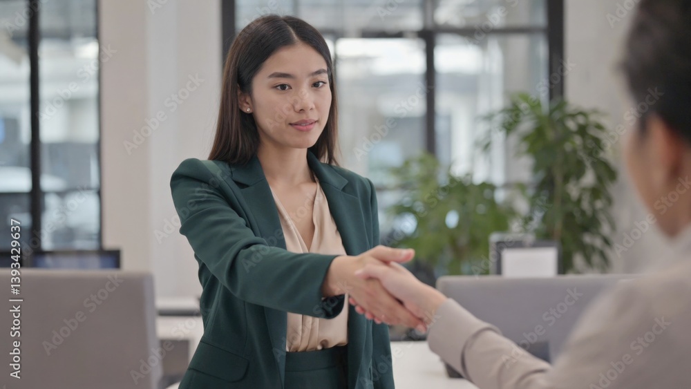 A woman and a man in a suit shake hands in a business meeting setting