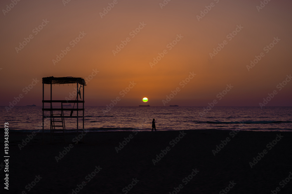 Scenic sunset over the sea in Albania. Vibrant sky with warm orange and pink hues reflecting on the calm water.