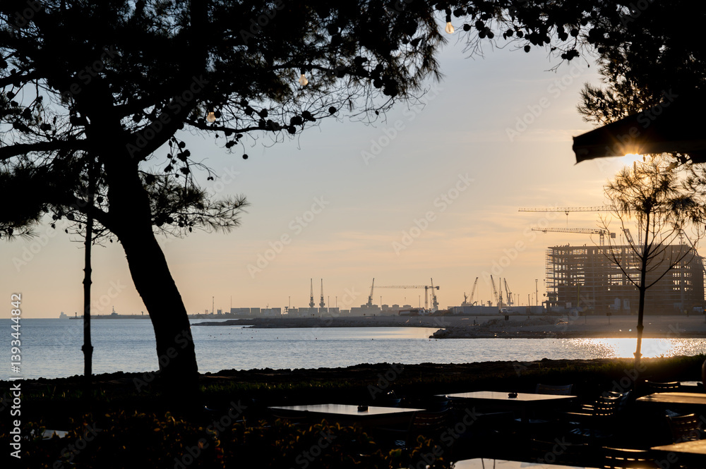 Construction on the seashore near the port of Durres, housing on the seashore. Silhouettes of construction cranes and house frames.