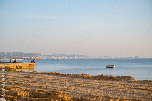 Obraz na płótnie The seashore is under reconstruction and the Adriatic shore in Durres. A fisherman catches fish from a pier. w salonie