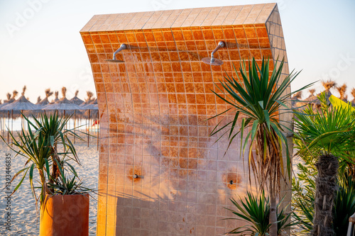 Obraz na płótnie Outdoor shower on a beach, fully tiled with ceramic tiles. Modern and functional seaside utility, designed for public use at a coastal resort or beachfront area. w salonie