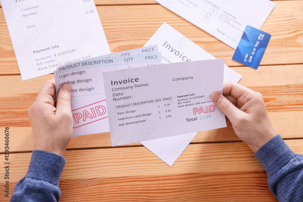 Obraz premium Paying bills. Man with credit card and invoices at wooden table, top view