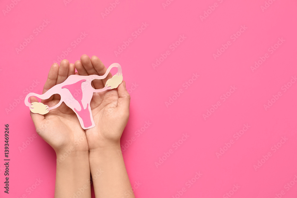 Female hands with paper uterus on pink background, closeup