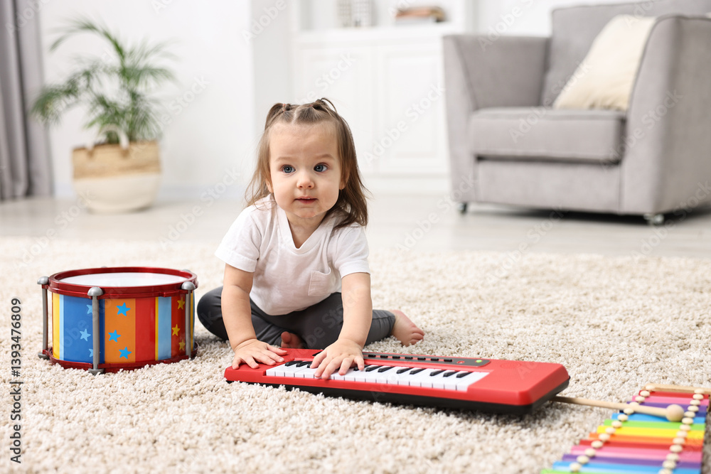 Cute little girl playing with toy piano at home