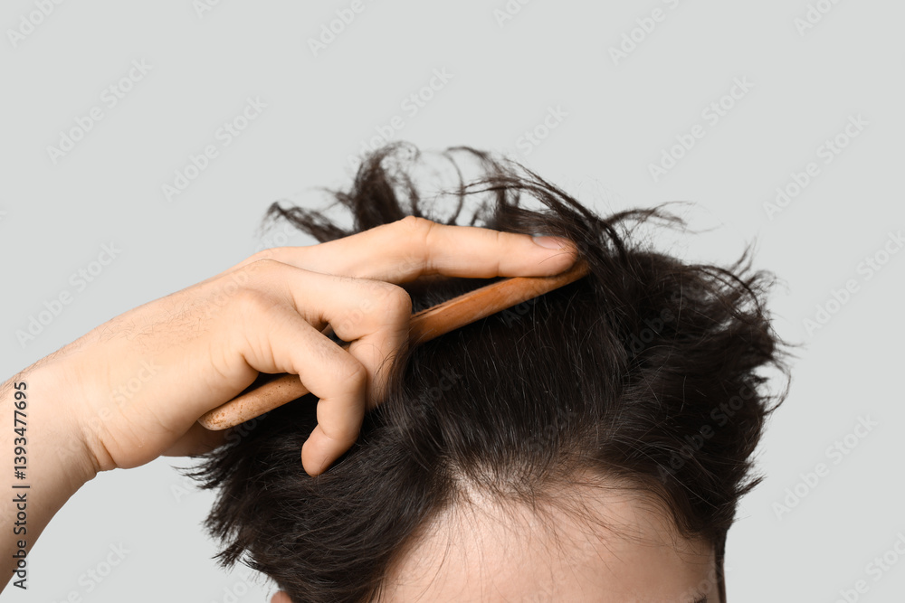 Young man combing hair on grey background, closeup Young man combing hair on grey background, closeup