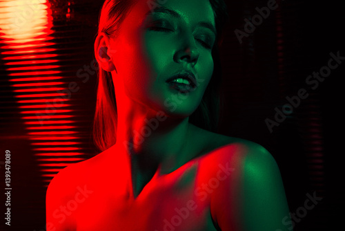Sensual young woman by vibrant neon red and green light creating a captivating and alluring in a dark backdrop.