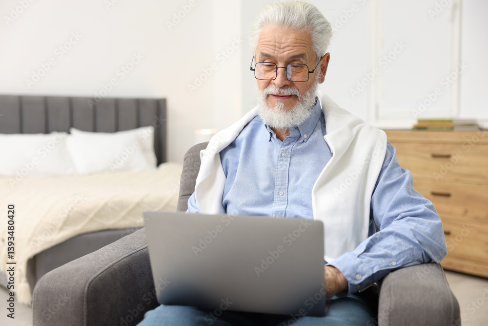 Bearded man with laptop in armchair at home Bearded man with laptop in armchair at home