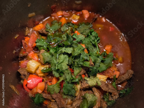 Obraz na płótnie Aromatic beef stew cooking in a pot, featuring tender beef, vibrant vegetables, and a sprinkle of fresh cilantro w salonie