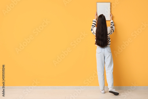 Young woman hanging picture...