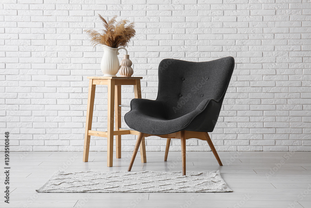 Cozy black armchair and pampas grass near white brick wall