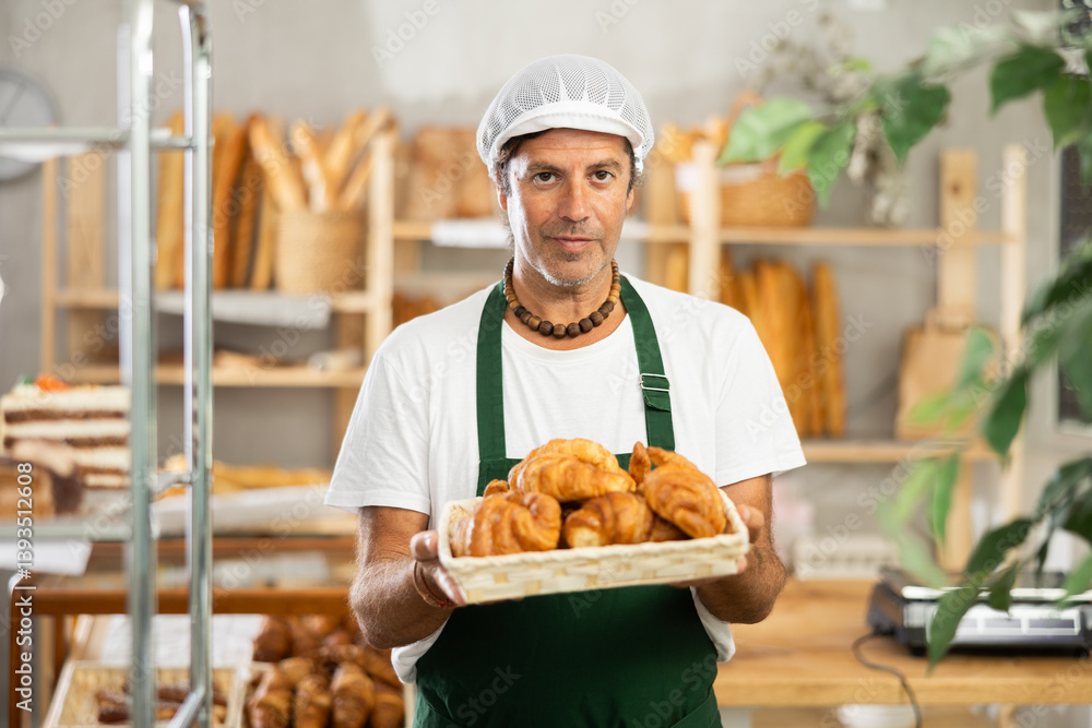 Portrait of a happy male baker offering to buy fresh delicious croissants in his bakery Portrait of a happy male baker offering to buy fresh delicious croissants in his bakery