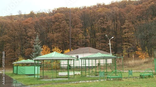 Wallpaper Mural A tranquil scene of an autumn park with green gazebos and benches. The background features a forest with trees in fall colors. Ideal for travel, nature, or seasonal themes.

 Torontodigital.ca