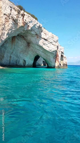 Blue caves as seen from a tourist speed boat. Limestone rock formations with visible cavities and caves dyed in fluorescent colour. Zakynthos island, Greece. Boat tour around island.
