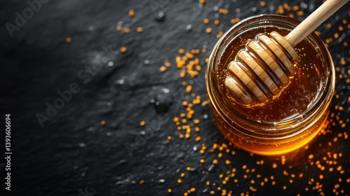 Honey in a glass jar with wooden dipper on dark slate background
