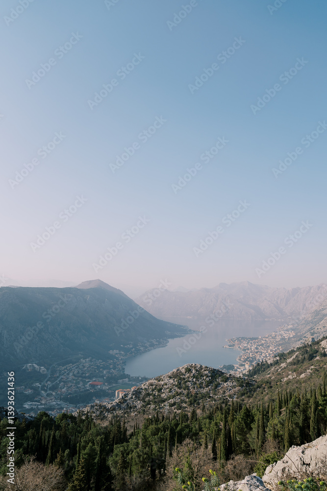 Obraz premium View from the mountain to the valley of the Bay of Kotor surrounded by mountains in a light haze. Montenegro