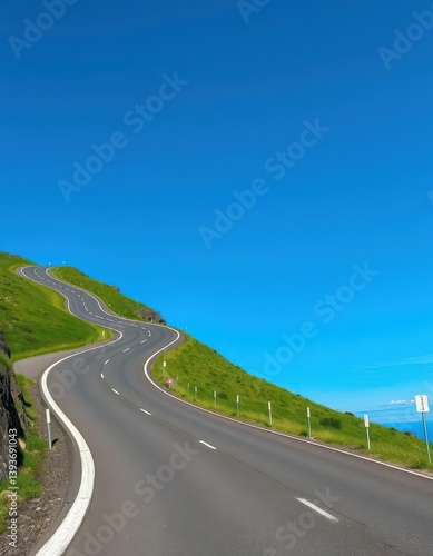 Winding asphalt road climbs a green hill against a vibrant blue sky, highway, countryside, sky