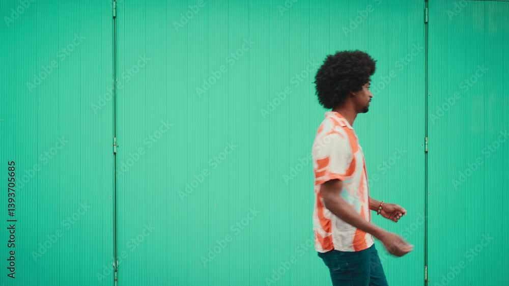 Cheerful young African American man in shirt goes dancing on light blue wall background. Urban lifestyle. Slow motion Cheerful young African American man in shirt goes dancing on light blue wall background. Urban lifestyle. Slow motion