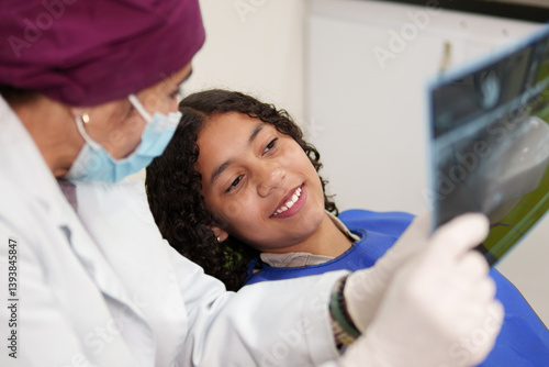 Dentist and young patient looking at dental x-ray during consultation in a dental clinic
