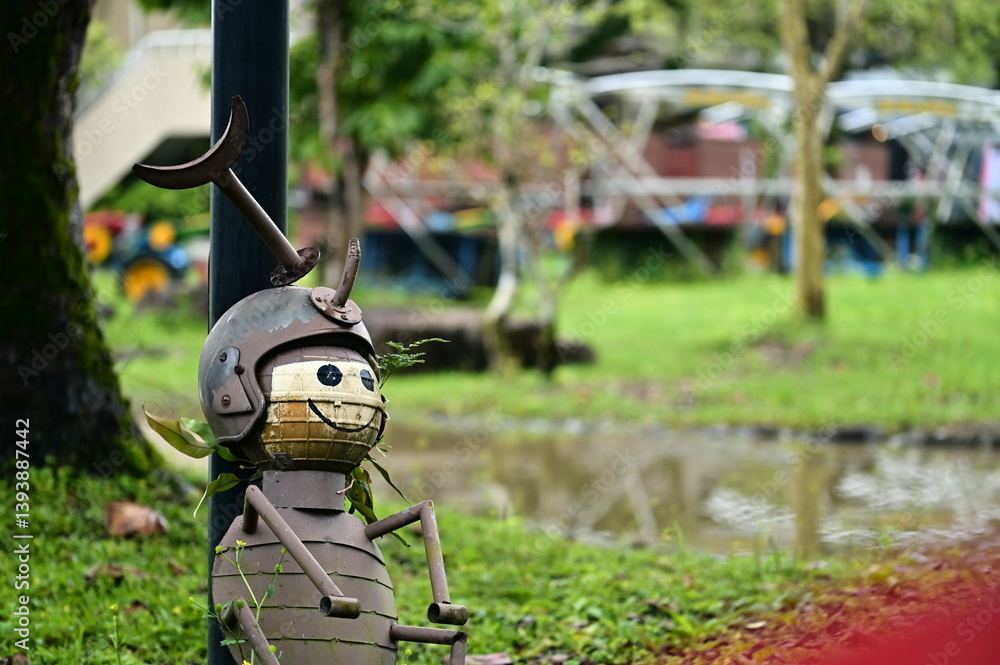 In the stillness of a rainy afternoon, this rhinoceros beetle figure on the lawn evokes childhood wonder and the quiet rhythm of nature.