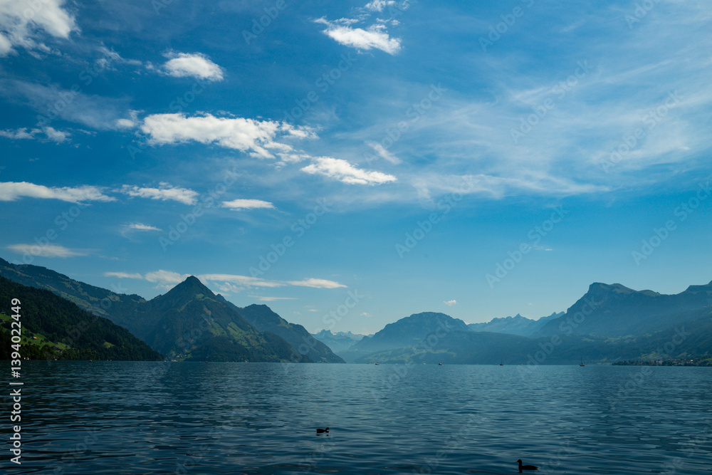 Alps mountain background. Swiss Alps mountain on sunny day. Mountain under clouds in blue sky. Blue nature background. Blue lake with sky near blue mountain.