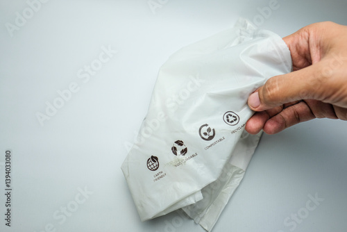 Hand Holding Biodegradable Plastic Bag with Eco-Friendly Symbols