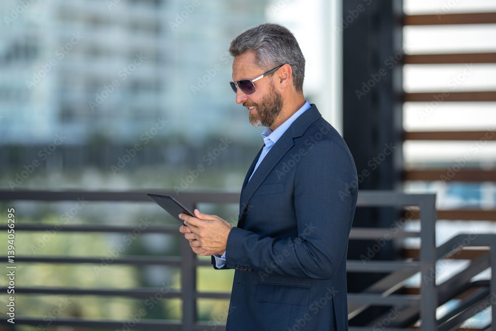 Urban entrepreneur reviewing business strategy. Businessman outdoors on tablet. Businessman using tablet outside. Businessman checking finance data. Rich businessman reviewing contract on tablet. Urban entrepreneur reviewing business strategy. Businessman outdoors on tablet. Businessman using tablet outside. Businessman checking finance data. Rich businessman reviewing contract on tablet.