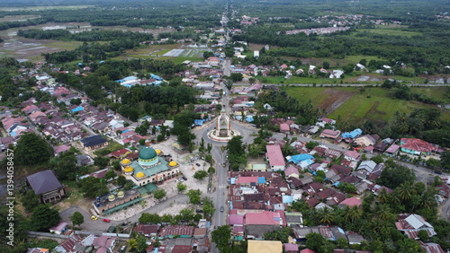 Rantau, Indonesia, 20 Desember 2024, Aerial view of city square roundabout with traffic activity and dense settlements around the roundabout