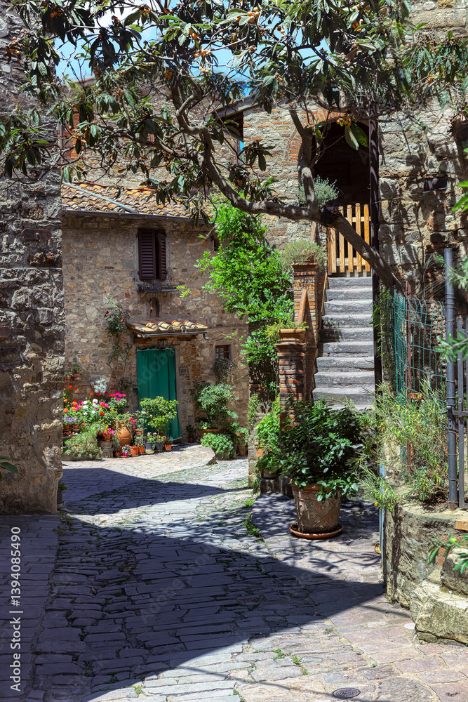 arrow cobblestone streets of Castello di Montefioralle, where medieval houses adorned vibrant flowers create a picturesque atmosphere in Tuscany. Greve in Chianti, Tuscany, Italy.
