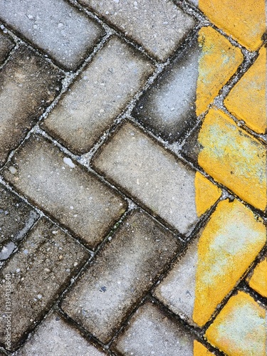 Background of a walkway or pavement with a herringbone-patterned gray and yellow tiled surface
