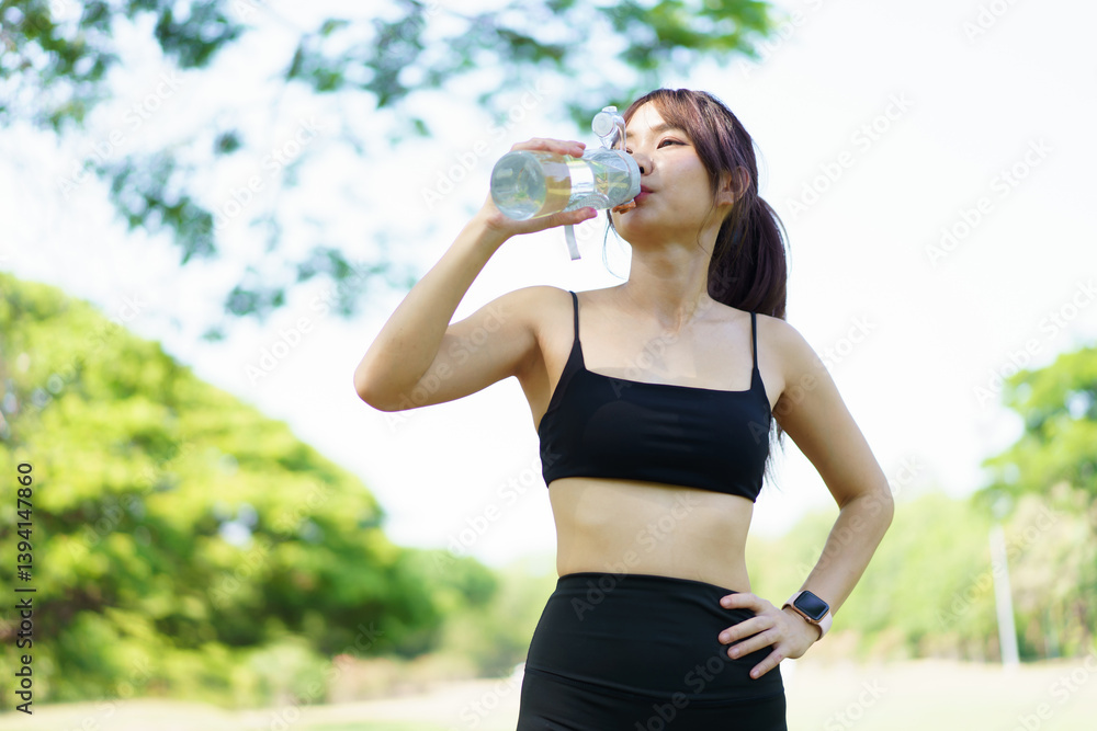 Asian woman take a break and drinks water from bottle after finished running. Asian woman take a break and drinks water from bottle after finished running.