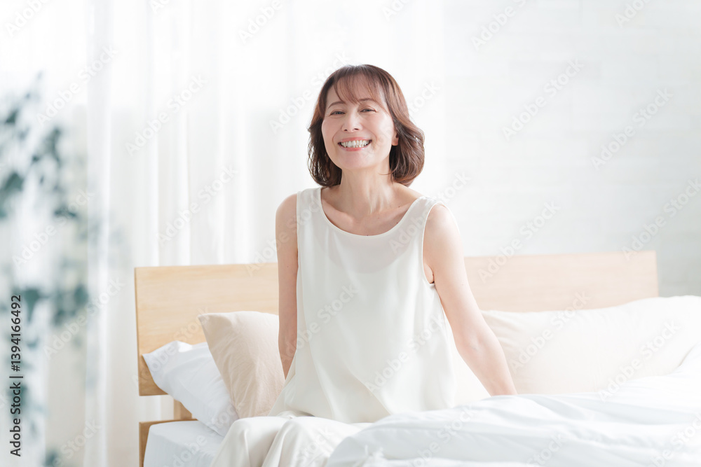 朝ベッドから起床する中高年女性 朝ベッドから起床する中高年女性