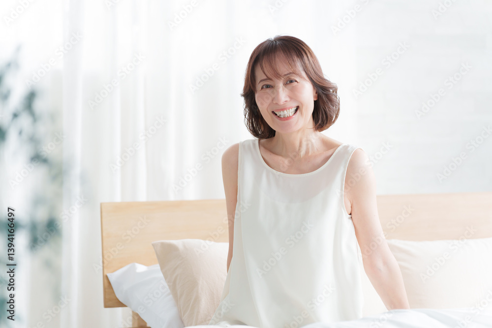 朝ベッドから起床する中高年女性 朝ベッドから起床する中高年女性