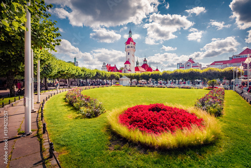 Sunny summer view of blooming flowers and wtite buildings in Dolny Sopot resort. Colrful afternoon scene of popular tourist destination - Sopot Pier (Molo in Sopot), Poland, Europe.