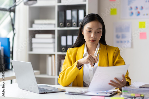 Serious female accountant working with financial documents in office and auditing accounts. Auditor checking financial report documents on desk.