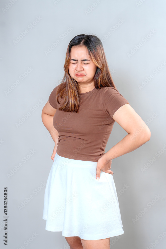 Disgusted young Asian woman grimacing and frowning with her eyes closed and hands on hips. Funny and expressive reaction face, concept of bad smell or uncomfortable situation. Disgusted young Asian woman grimacing and frowning with her eyes closed and hands on hips. Funny and expressive reaction face, concept of bad smell or uncomfortable situation.