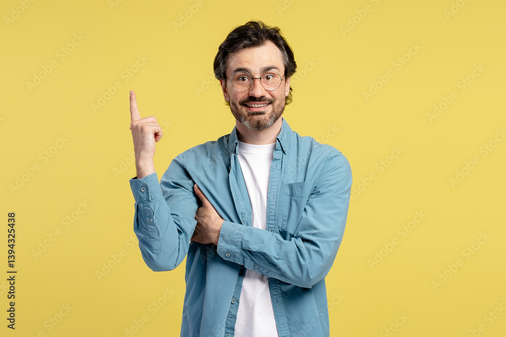Smart casual man pointing up having an idea on yellow background Smart casual man pointing up having an idea on yellow background