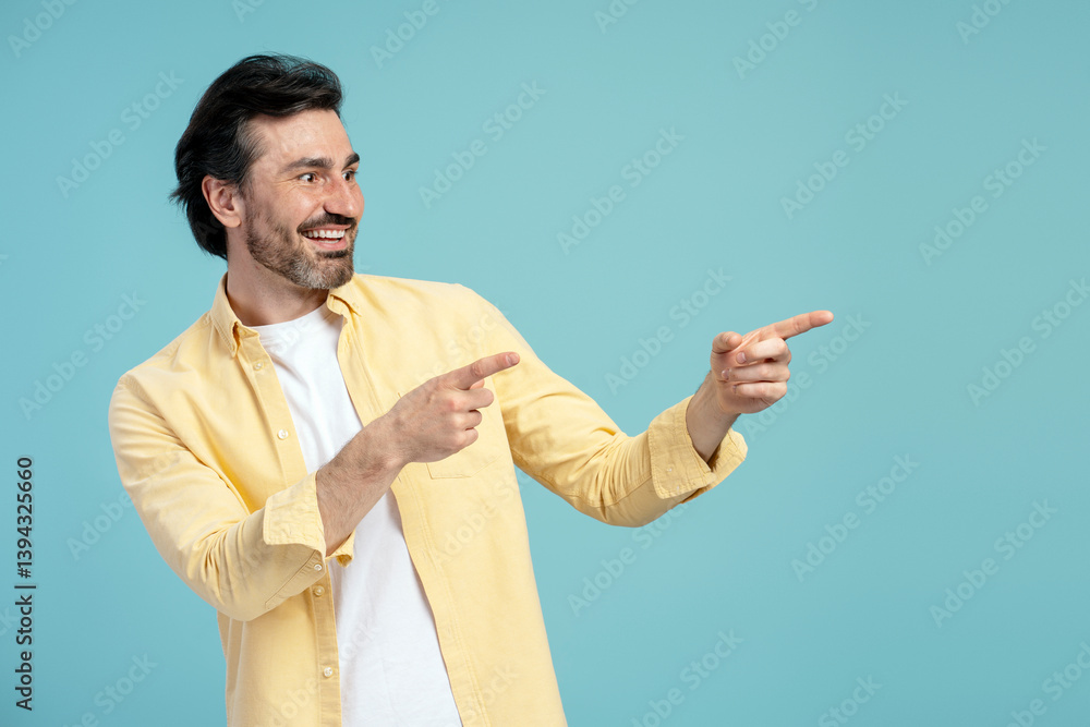 Cheerful man pointing aside with both index fingers on blue background Cheerful man pointing aside with both index fingers on blue background