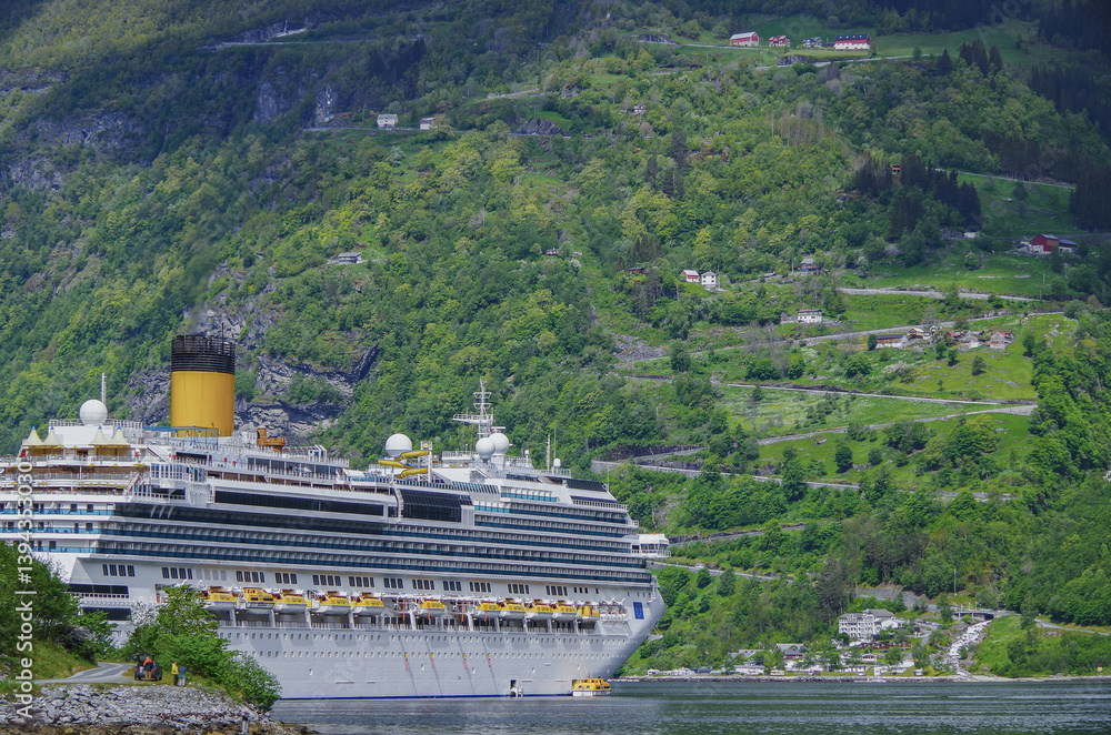 Modern mega cruiseship cruise ship liner Favolosa in Geirangerfjord with panoramic views of Geiranger and the breathtaking mountain scenery and fjord landscape nature during Norway cruising