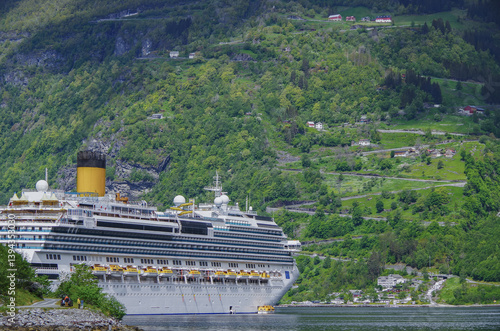 Obraz na płótnie Modern mega cruiseship cruise ship liner Favolosa in Geirangerfjord with panoramic views of Geiranger and the breathtaking mountain scenery and fjord landscape nature during Norway cruising w salonie