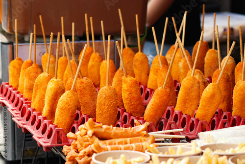 Corndogs fried dry on bamboo skewers, served with a spread of sauce, cheap street food, crispy and savory