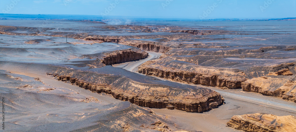 A winding road leads through the unique Yardang landform in Xinjiang. Famous Dahaidao no man's land natural scenery in China.