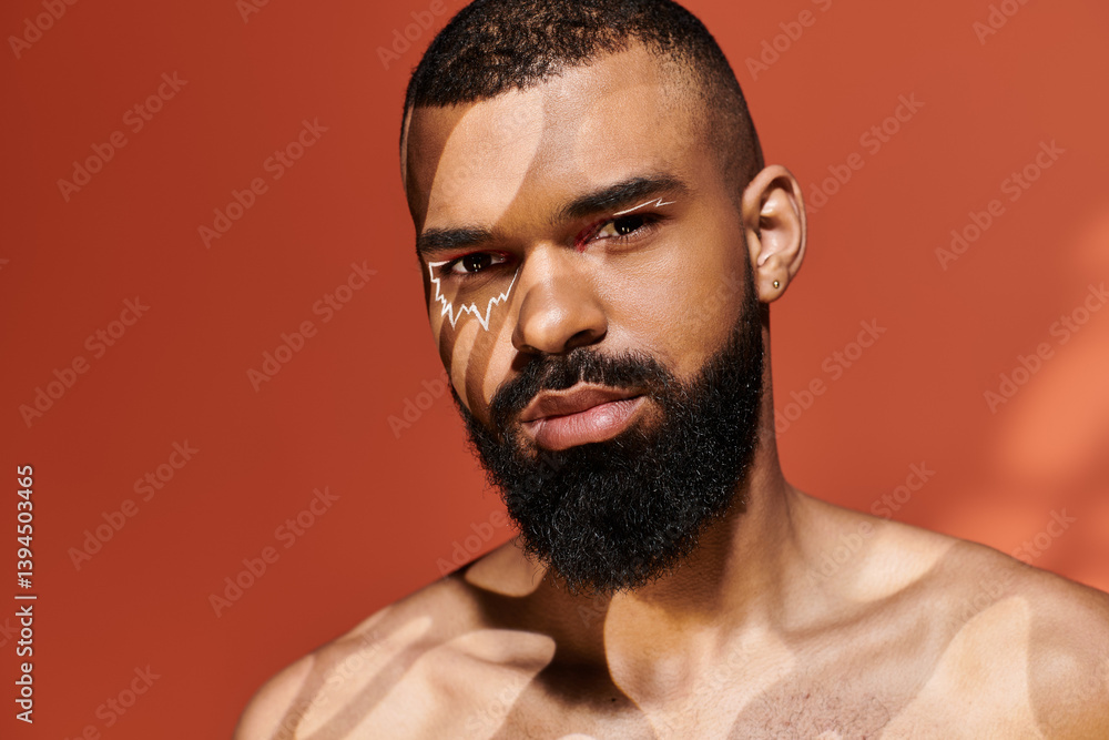 Obraz premium Stylish young man exuding confidence under playful sunlight patterns in a vibrant orange backdrop