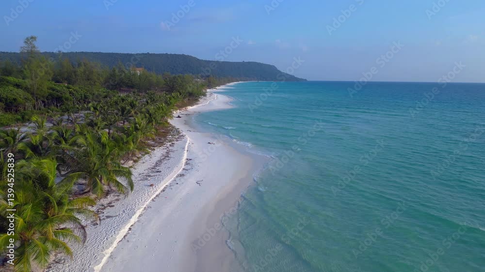 a pristine beach with palm trees meeting the crystal clear turquoise water on Koh Rong island, Cambodia. Lovely aerial view flight descending drone a pristine beach with palm trees meeting the crystal clear turquoise water on Koh Rong island, Cambodia. Lovely aerial view flight descending drone
