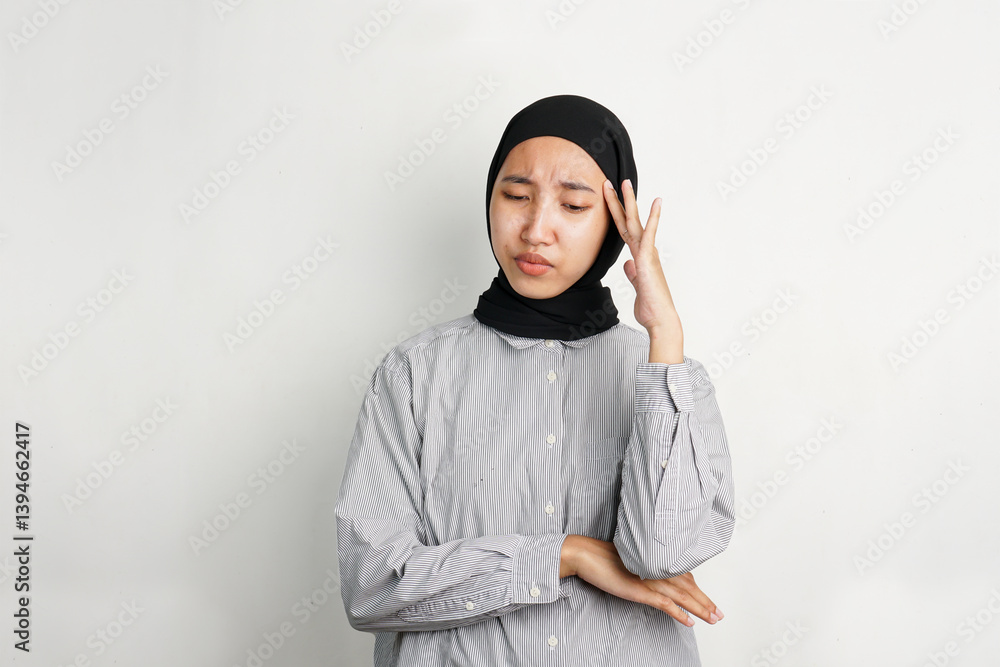 Young Asian woman touching her temple with a pained expression, indicating dizziness or headache, standing alone in front of a plain background with a confused and uncomfortable look. Young Asian woman touching her temple with a pained expression, indicating dizziness or headache, standing alone in front of a plain background with a confused and uncomfortable look.