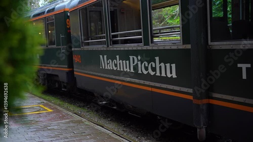 Passenger Train with Machu Picchu Sign on the Tracks in Aguas Calientes, Peru During Rain