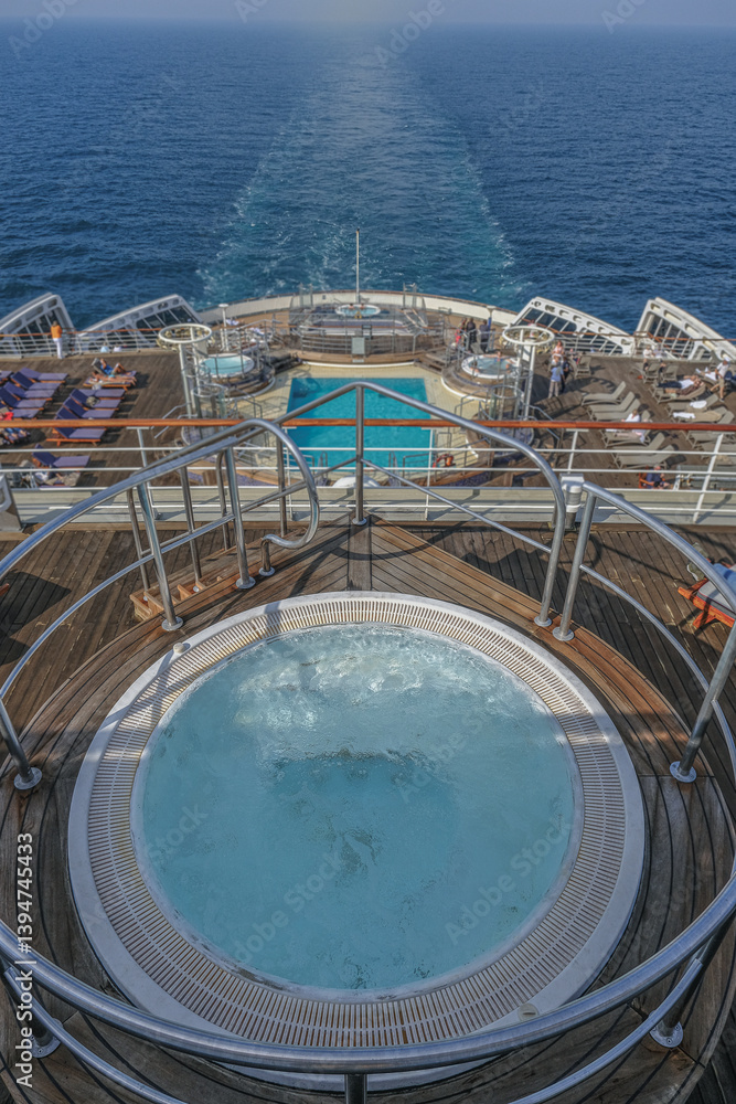 Views onto outdoor teak balcony terrace veranda promenade sun pool deck of ocean liner cruiseship cruise ship with chairs loungers at sea during Transatlantic Crossing to New York on beautiful sun day