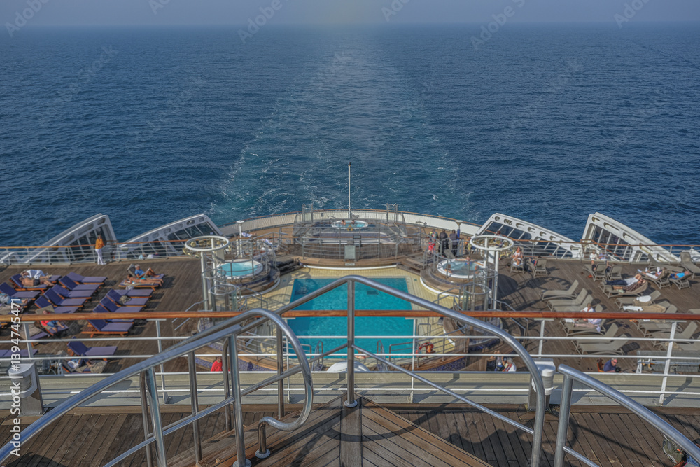 Views onto outdoor teak balcony terrace veranda promenade sun pool deck of ocean liner cruiseship cruise ship with chairs loungers at sea during Transatlantic Crossing to New York on beautiful sun day