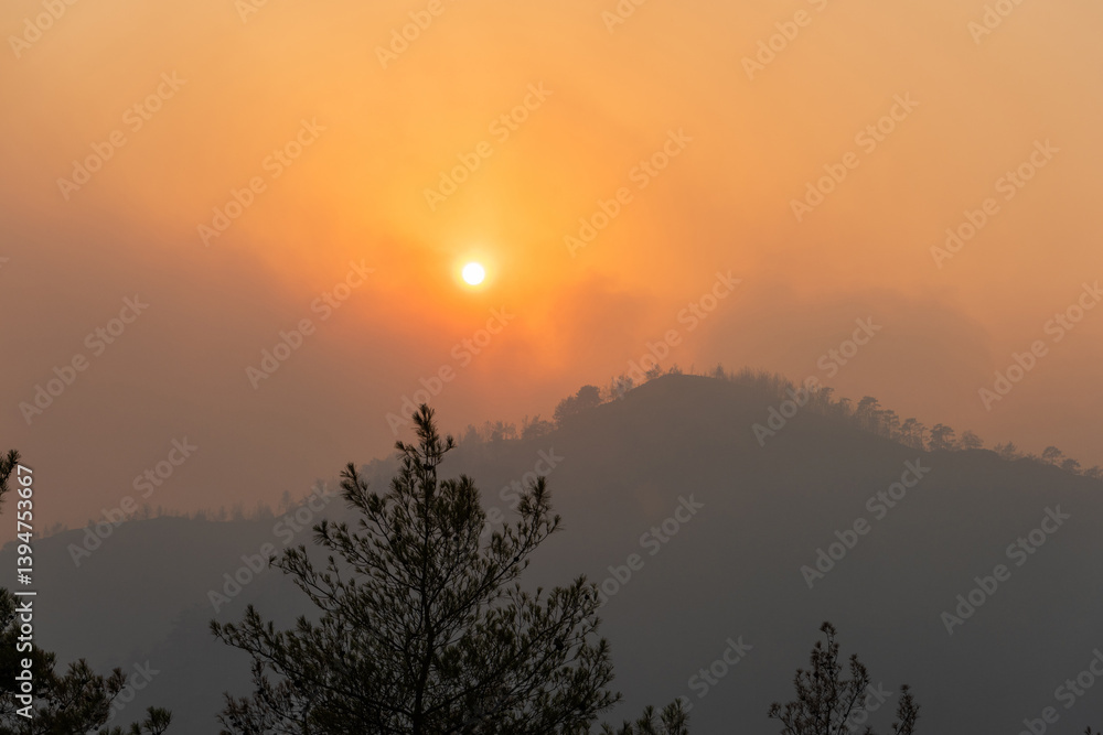 Naklejka premium Sun shining through a cloud of smoke in Marmaris resort town of Turkey, following forest fires of July-August 2021.