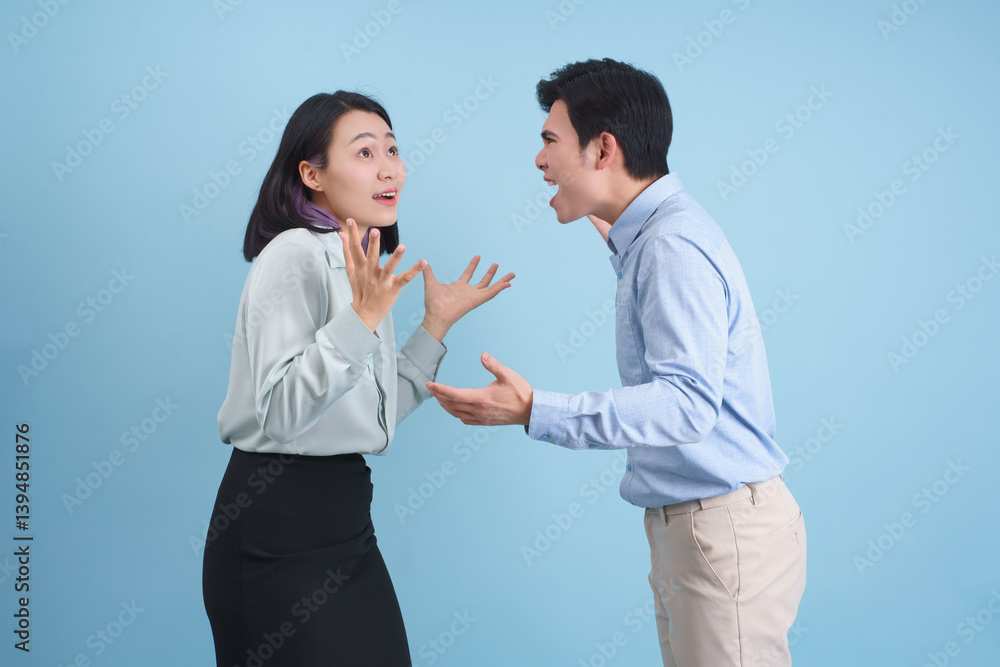 Couple engaged in a heated conversation in a studio with a blue background Couple engaged in a heated conversation in a studio with a blue background