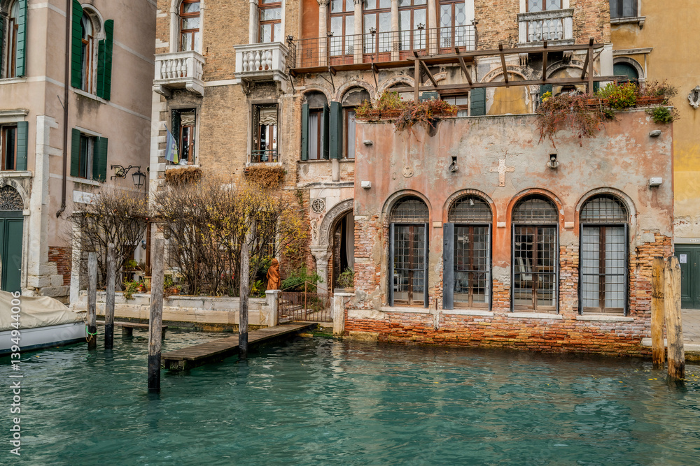 Historic canal-side building in Venice with weathered brick and arched windows reflecting in water. Venice, Italy Historic canal-side building in Venice with weathered brick and arched windows reflecting in water. Venice, Italy